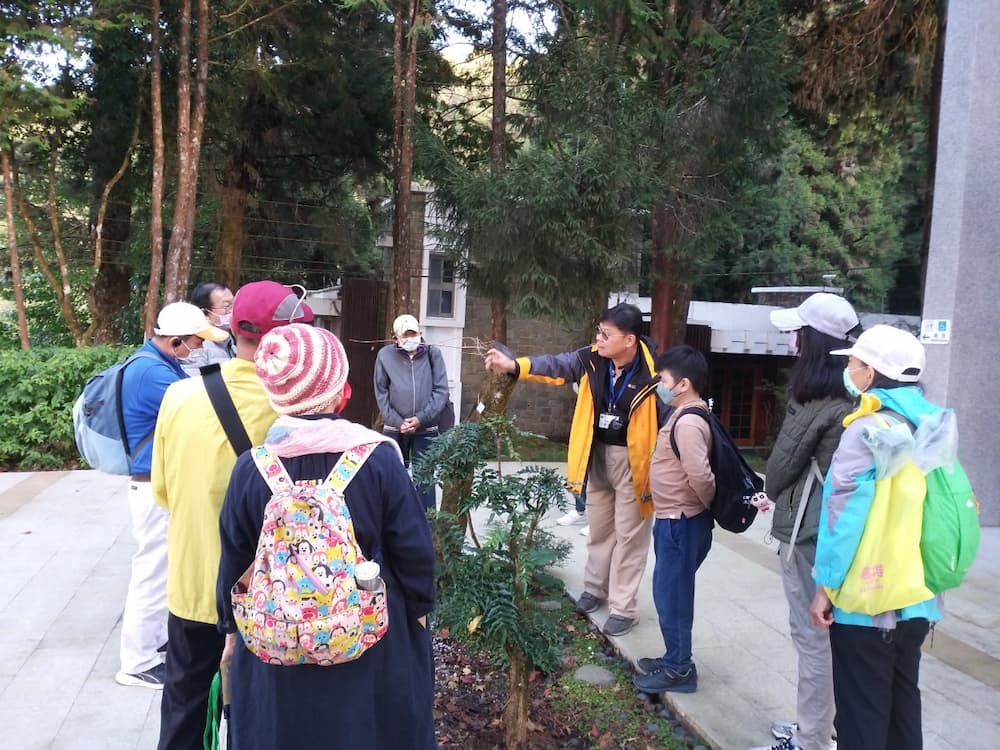 郭盈良理事長解說阿里山生態,在阿里山生態館前介紹阿里山十大功勞及櫻花樹
